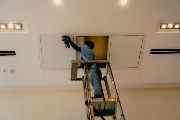 Technician from an air duct cleaning company in California cleaning residential ductwork