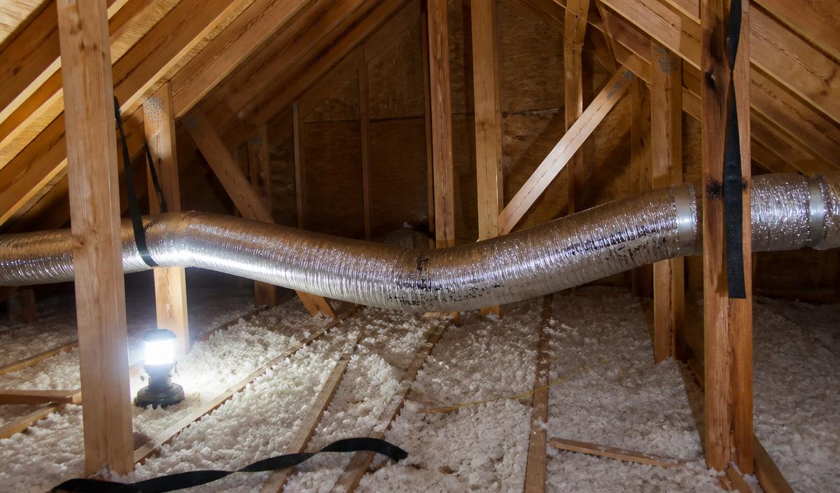 Long dryer duct sagging between attic trusses in a Denair ranch home, a common spot for lint to collect.